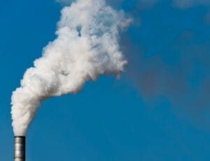 A large cloud of smoke shown leaving a manufacturing facility.